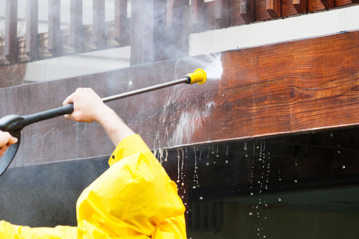 Pressure washer cleaning house exterior edge of deck