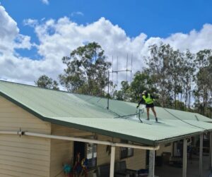 pressure washer washing metal roof by climbing on the roof while power washing