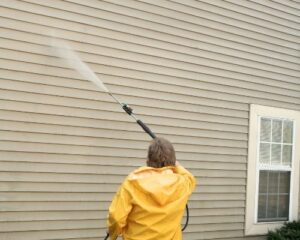Exterior house cleaning by a man wearing a yellow rainjacket